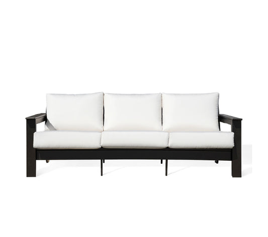  Front view of Hazelnut Polymer Outdoor Sofa showcasing a modern, low-slung frame with a wood grain finish, plush Sunbrella® Canvas Granite cushions, and wide arms for added comfort, Oakville, ON.